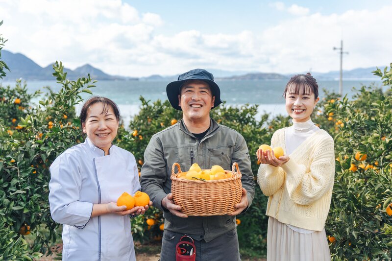 瀬戸田の柑橘畑で生産者と収穫した柑橘を持つようす
